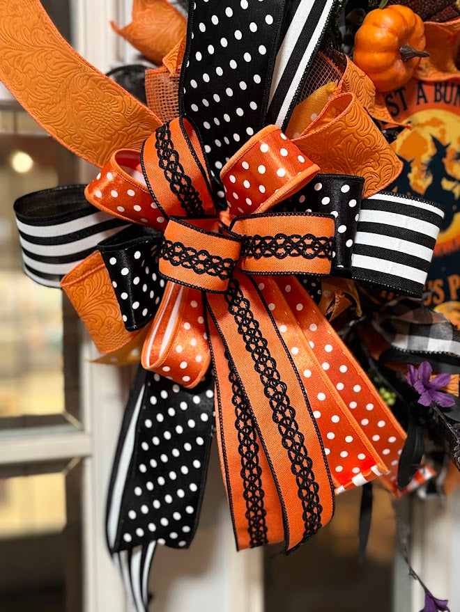 Close-up of Halloween bow with orange polka dot, black and white stripe, and lace ribbons