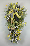 Sunny Days Swag full view with black and yellow ribbon bow and lush greenery
